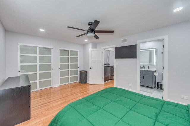 bedroom with visible vents, a sink, light wood-style floors, and washer / dryer