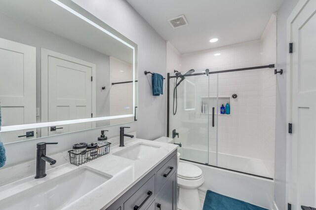 bathroom featuring visible vents, a sink, enclosed tub / shower combo, and toilet