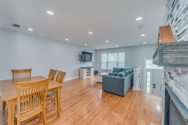 living room with recessed lighting, visible vents, a stone fireplace, and light wood finished floors