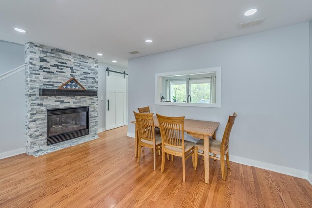 dining area with baseboards, visible vents, a barn door, and wood finished floors