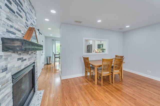 dining room with a fireplace, light wood-style flooring, recessed lighting, baseboards, and visible vents