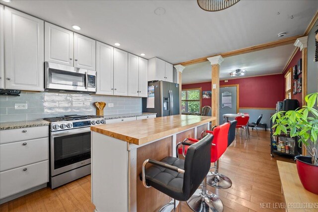 3005 Starling Ln, Rolling Meadows, IL 60008 - kitchen with appliances with stainless steel finishes, wooden counters, ornate columns, a breakfast bar area, and white cabinets