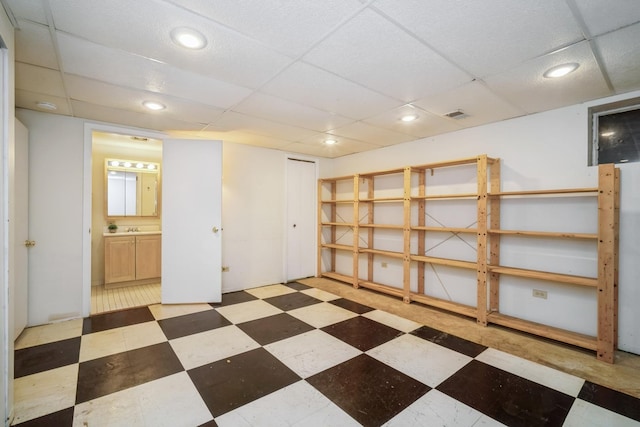 finished below grade area with tile patterned floors, recessed lighting, and a paneled ceiling