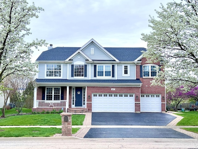 view of front facade with a garage, covered porch, driveway, and a front yard