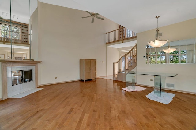 7017 Plymouth Ct, Tinley Park, IL 60477 - unfurnished living room featuring a ceiling fan, plenty of natural light, stairs, a towering ceiling, and wood finished floors