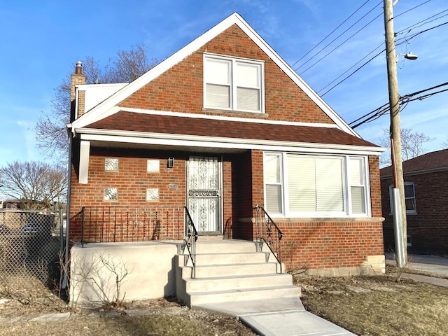 bungalow-style house with brick siding, fence, and a chimney