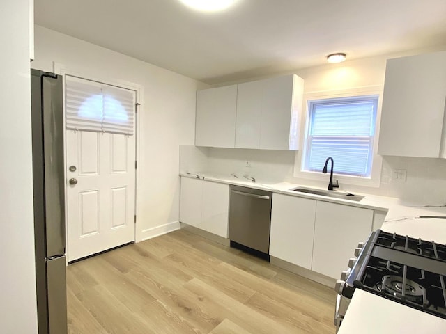 kitchen with light countertops, white cabinetry, a sink, light wood finished floors, and stainless steel appliances