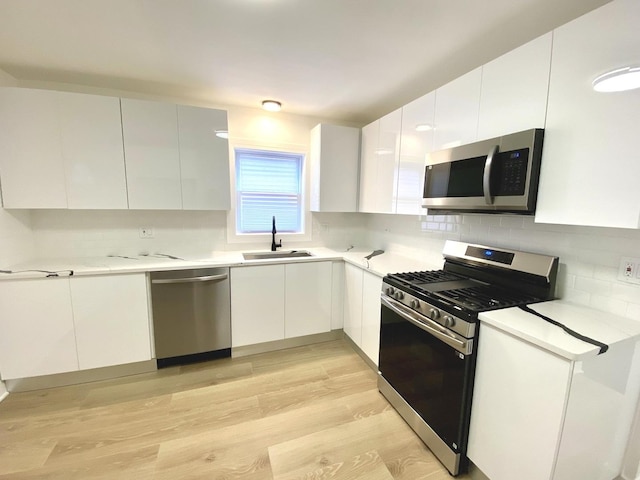 kitchen featuring white cabinets, appliances with stainless steel finishes, a sink, and tasteful backsplash