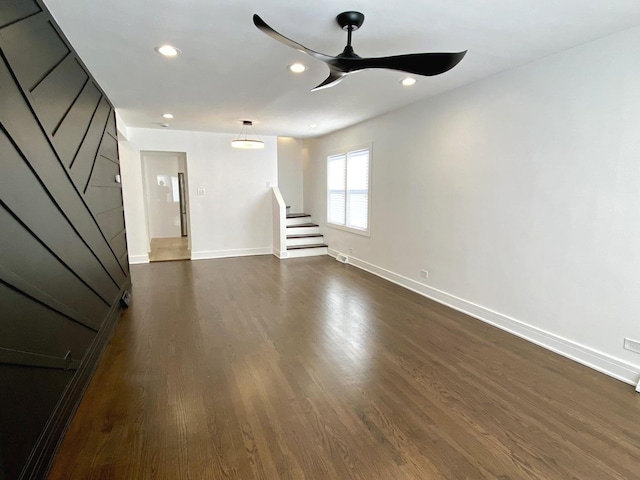 unfurnished living room with a ceiling fan, dark wood finished floors, stairs, baseboards, and recessed lighting