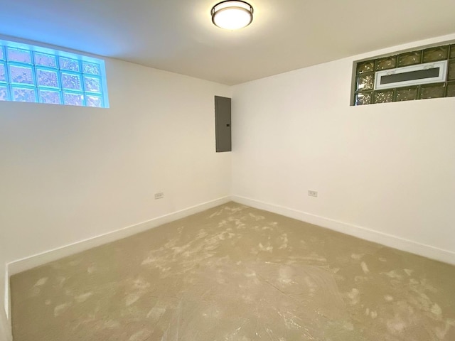 basement with baseboards, electric panel, and carpet flooring