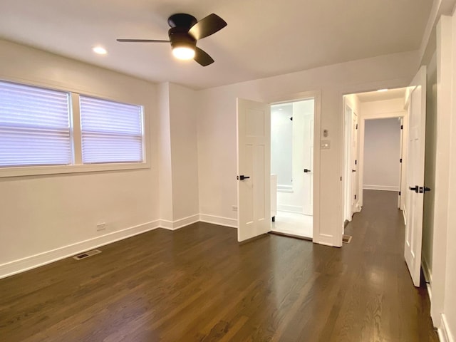 unfurnished bedroom with visible vents, a ceiling fan, dark wood finished floors, and baseboards