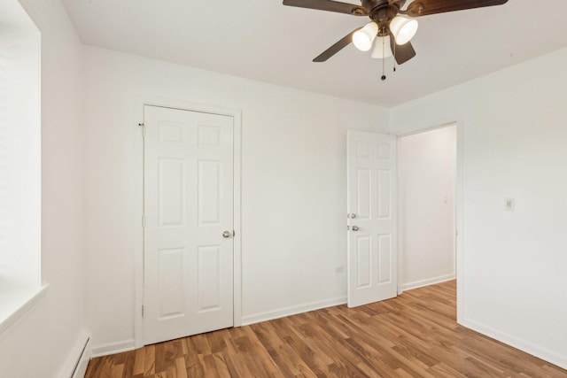 8440 Skokie Blvd Unit 102, Skokie, IL 60077 - unfurnished bedroom featuring wood finished floors, a baseboard radiator, baseboards, and a ceiling fan