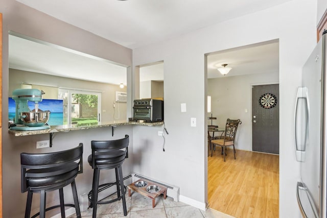 829 S Dwyer Ave Unit B, Arlington Heights, IL 60005 - kitchen featuring freestanding refrigerator, a breakfast bar, stone countertops, and light wood-style floors