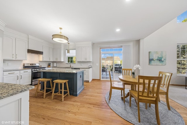 kitchen featuring stainless steel gas range oven, white cabinets, range hood, light wood-style flooring, and recessed lighting