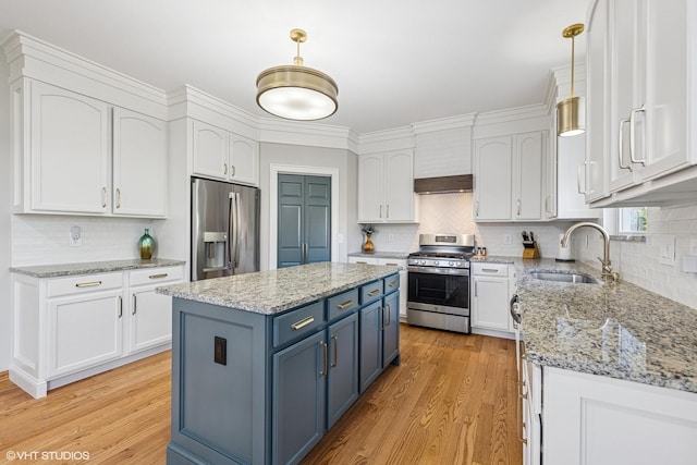 kitchen with stainless steel appliances, a sink, blue cabinetry, white cabinets, and light wood-style floors