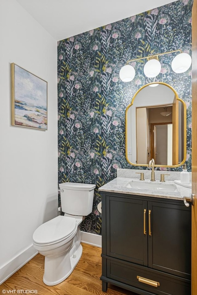 bathroom with wallpapered walls, baseboards, toilet, and wood finished floors