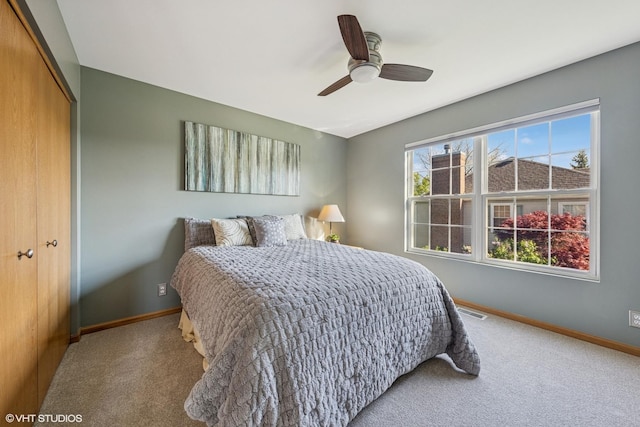 carpeted bedroom featuring a closet, baseboards, and a ceiling fan