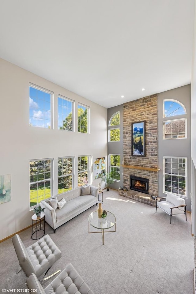 living area featuring carpet floors, healthy amount of natural light, a towering ceiling, a fireplace, and baseboards