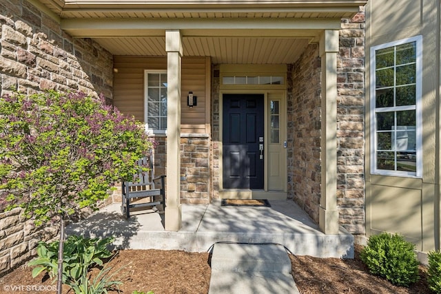 view of exterior entry featuring stone siding and covered porch
