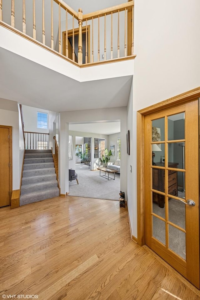 entryway with a towering ceiling, stairs, baseboards, and wood finished floors