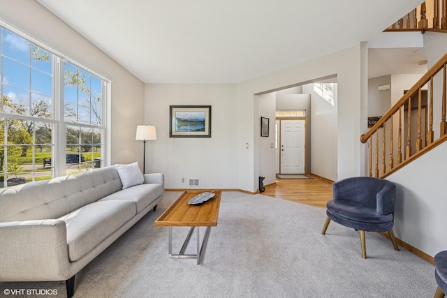 living room featuring carpet flooring, baseboards, and stairway