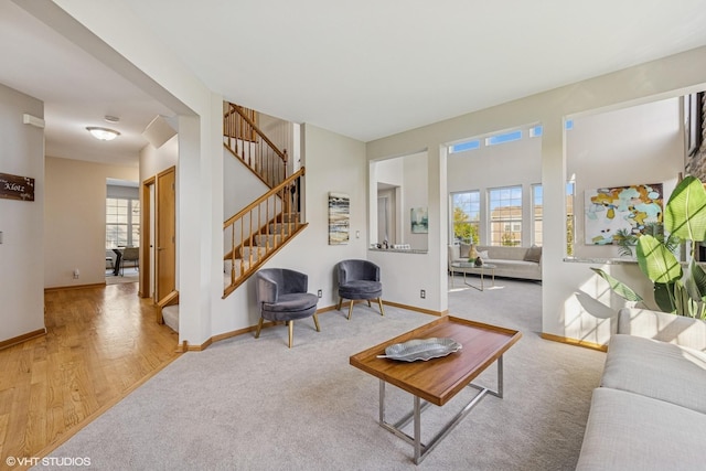 living room with healthy amount of natural light, light colored carpet, stairway, and baseboards