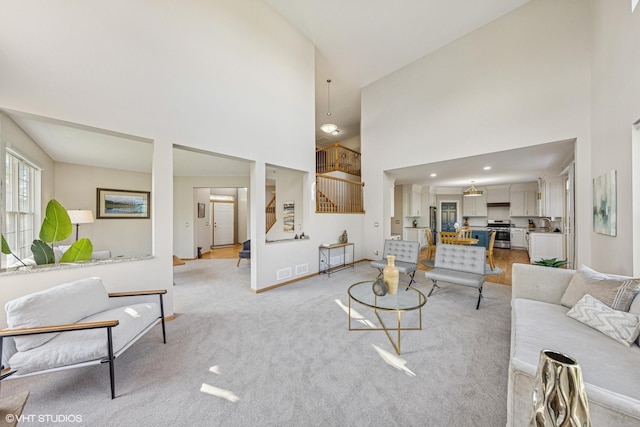 living room featuring a high ceiling, stairs, baseboards, and light colored carpet