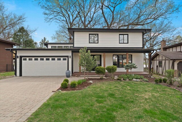 traditional home featuring a porch, decorative driveway, an attached garage, and a front yard