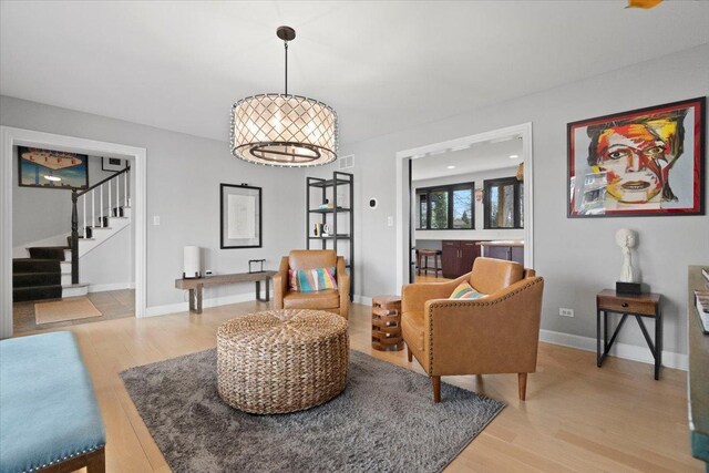 living area with stairway, baseboards, and light wood-type flooring
