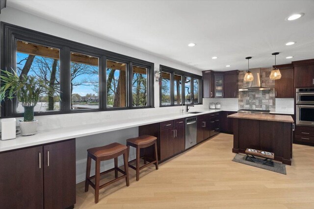 kitchen featuring a sink, stainless steel appliances, recessed lighting, and wall chimney exhaust hood