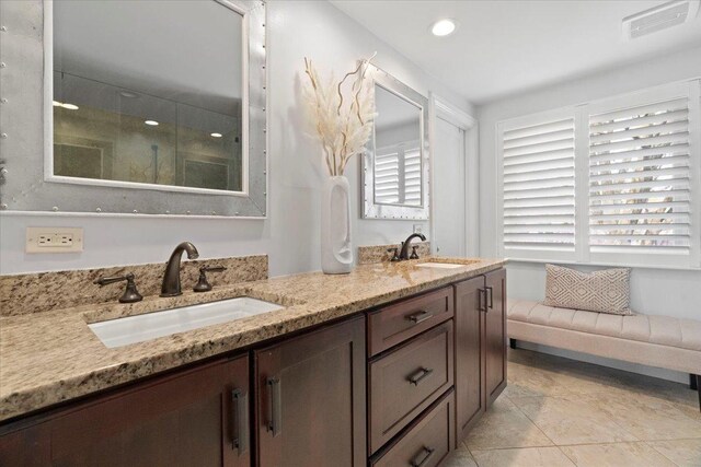 bathroom with visible vents, a sink, walk in shower, and double vanity