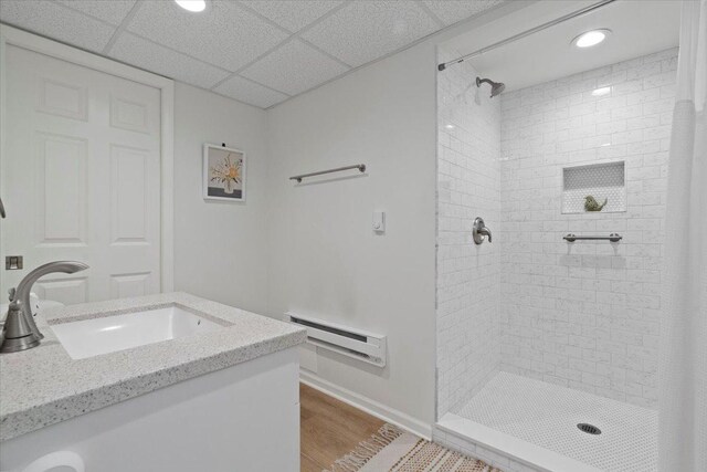 bathroom with wood finished floors, baseboards, recessed lighting, a sink, and a tile shower
