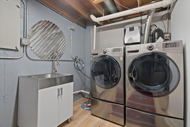 laundry room with laundry area, a sink, light wood-style floors, and washing machine and clothes dryer