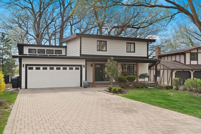 traditional-style house with covered porch, decorative driveway, a garage, and a front lawn