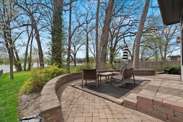 view of patio / terrace with outdoor dining area, a water view, and fence