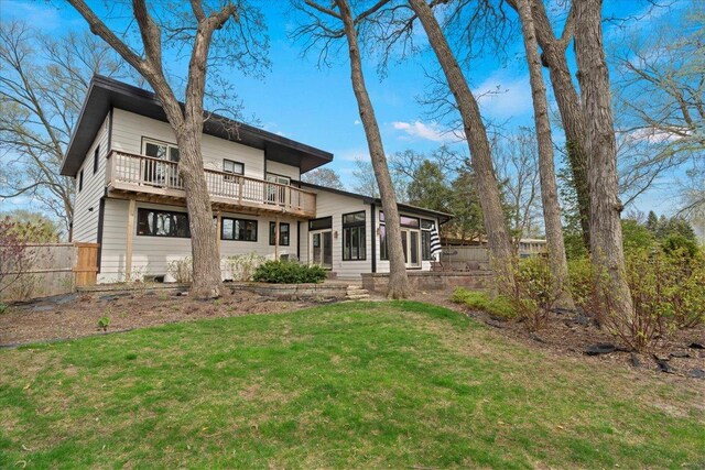back of house featuring a lawn, fence, and a balcony