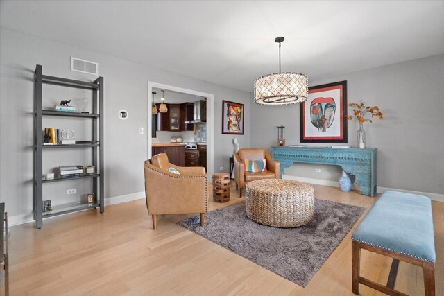 sitting room featuring baseboards, visible vents, and wood finished floors
