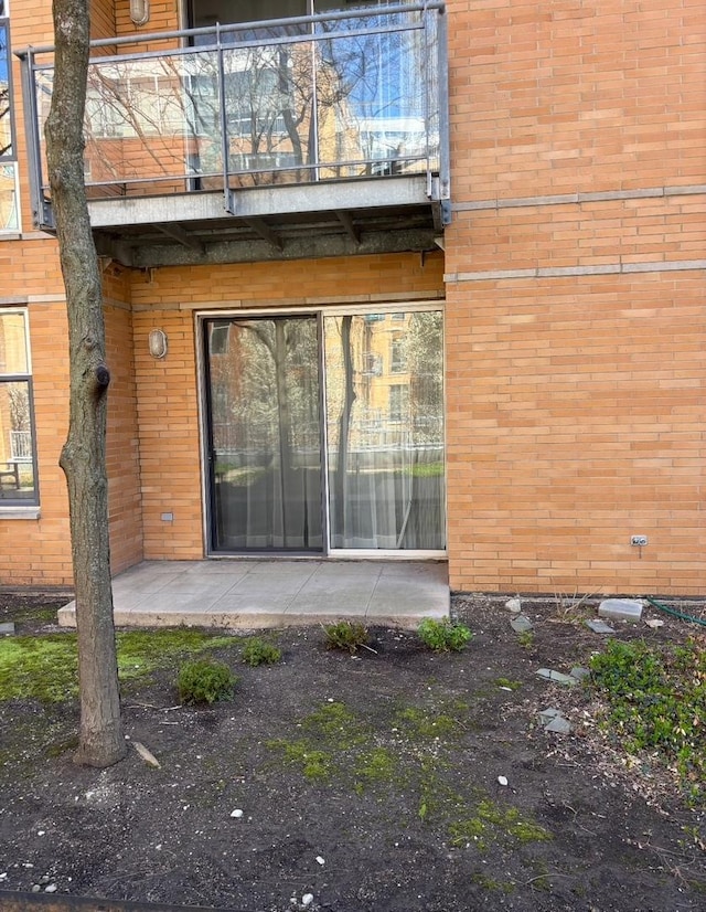 doorway to property featuring a patio, a balcony, and brick siding