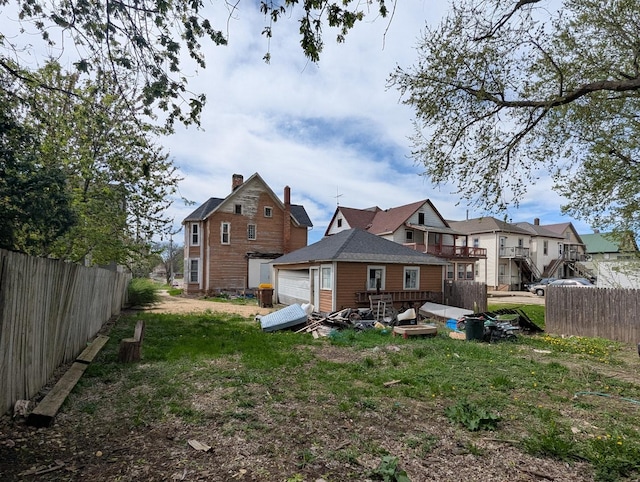 rear view of house featuring fence, a wooden deck, and a lawn