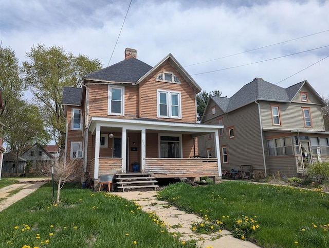 view of front of house featuring a shingled roof, a front yard, covered porch, and a chimney