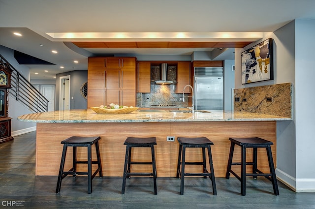600 N Kingsbury St Unit 1902, Chicago, IL 60654 - kitchen with brown cabinets, wall chimney exhaust hood, baseboards, backsplash, and stainless steel built in refrigerator