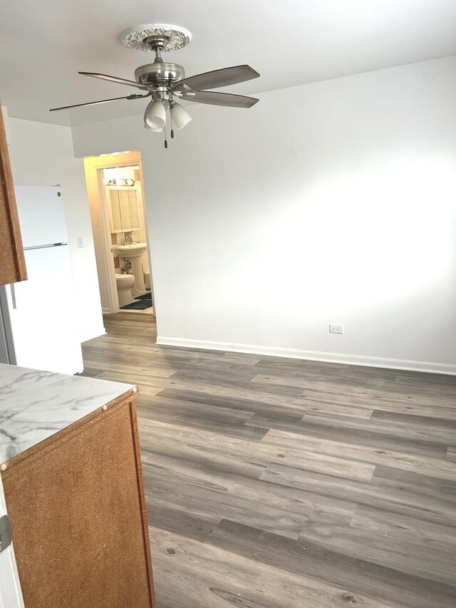 interior space featuring baseboards, a ceiling fan, and wood finished floors
