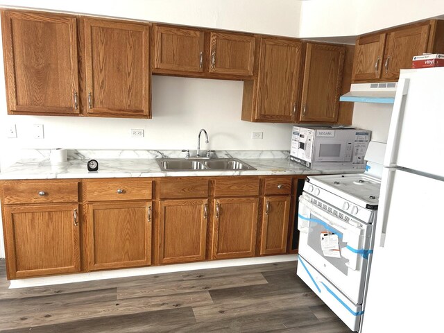kitchen featuring white appliances, under cabinet range hood, a sink, and light countertops