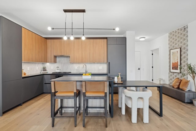 kitchen featuring modern cabinets, tasteful backsplash, light wood-style flooring, and hanging light fixtures