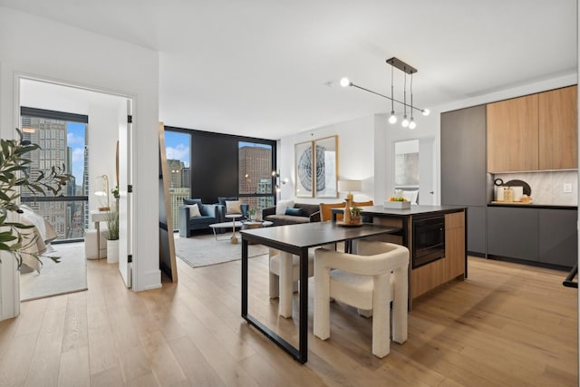 kitchen with modern cabinets, black microwave, dark countertops, and light wood-type flooring