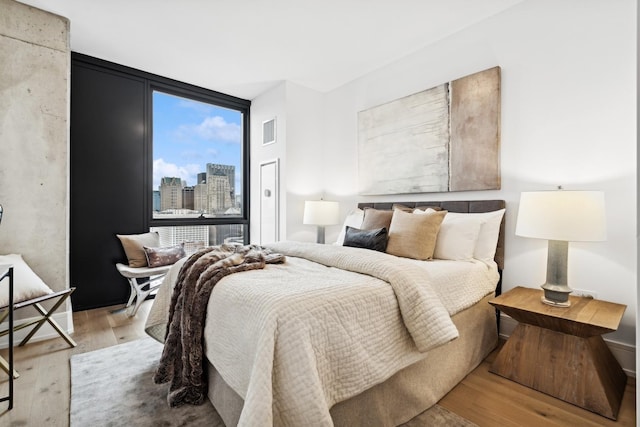 bedroom with wood finished floors and a view of city