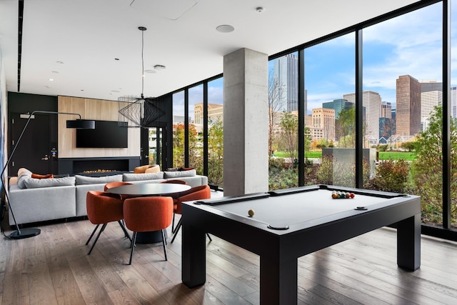 game room with a city view, expansive windows, hardwood / wood-style floors, and a notable chandelier