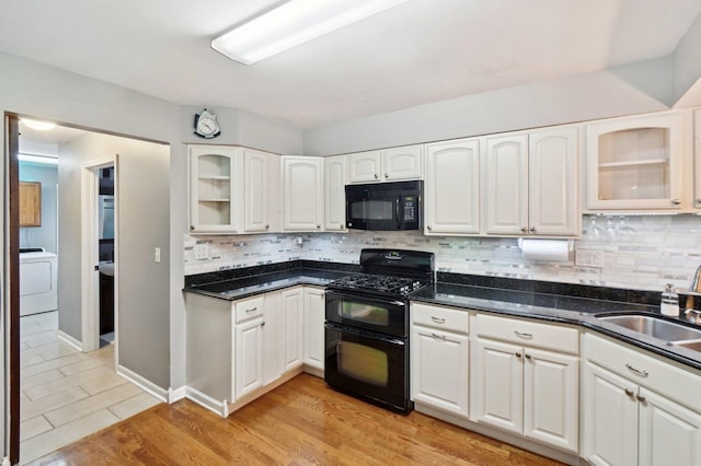 kitchen with washer / clothes dryer, tasteful backsplash, a sink, white cabinets, and black appliances
