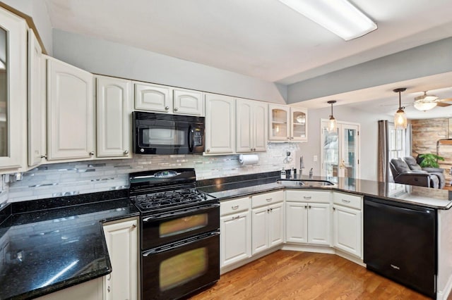 kitchen with a sink, light wood-style floors, a peninsula, glass insert cabinets, and black appliances