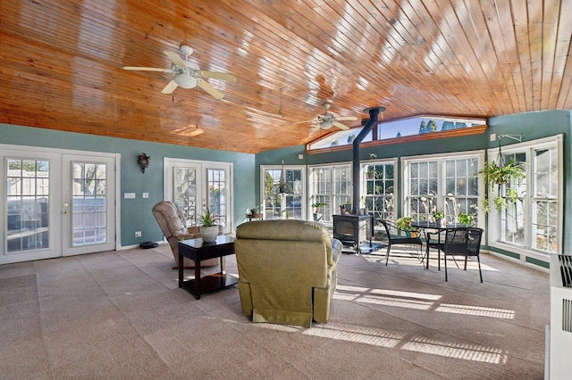 interior space with wood ceiling, a ceiling fan, french doors, a wood stove, and lofted ceiling